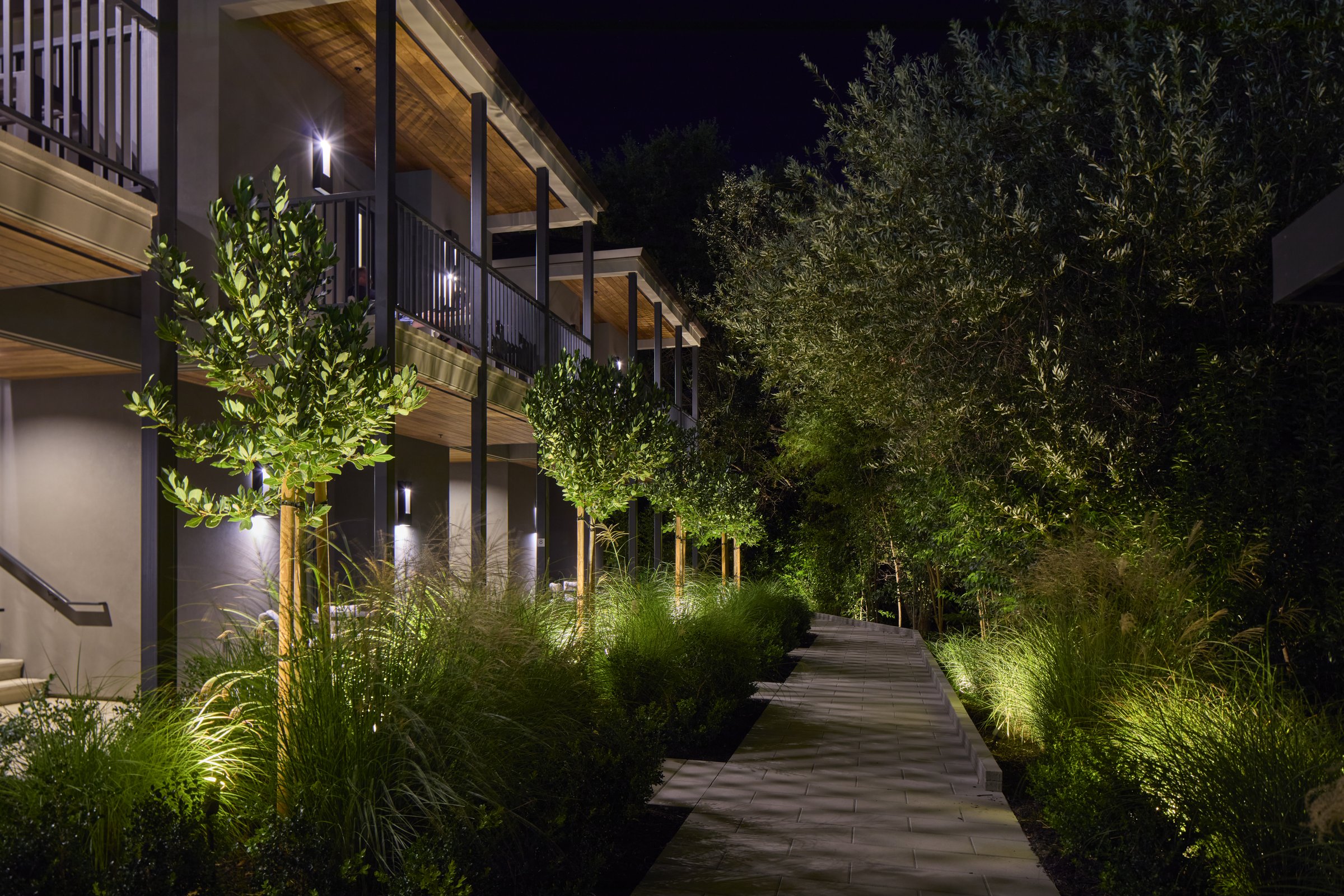 The Creekside Suites and lit walkway at night.