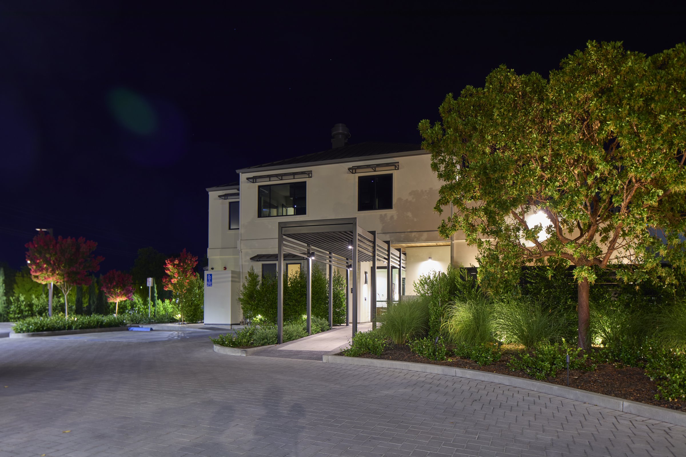 The lobby building entry and its illuminated pergola at night.