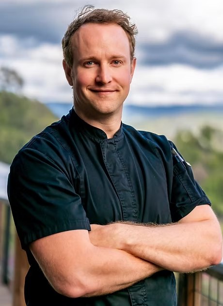 Chef David Carey of Camber Events, arms crossed, with the hills of Wine Country behind him.