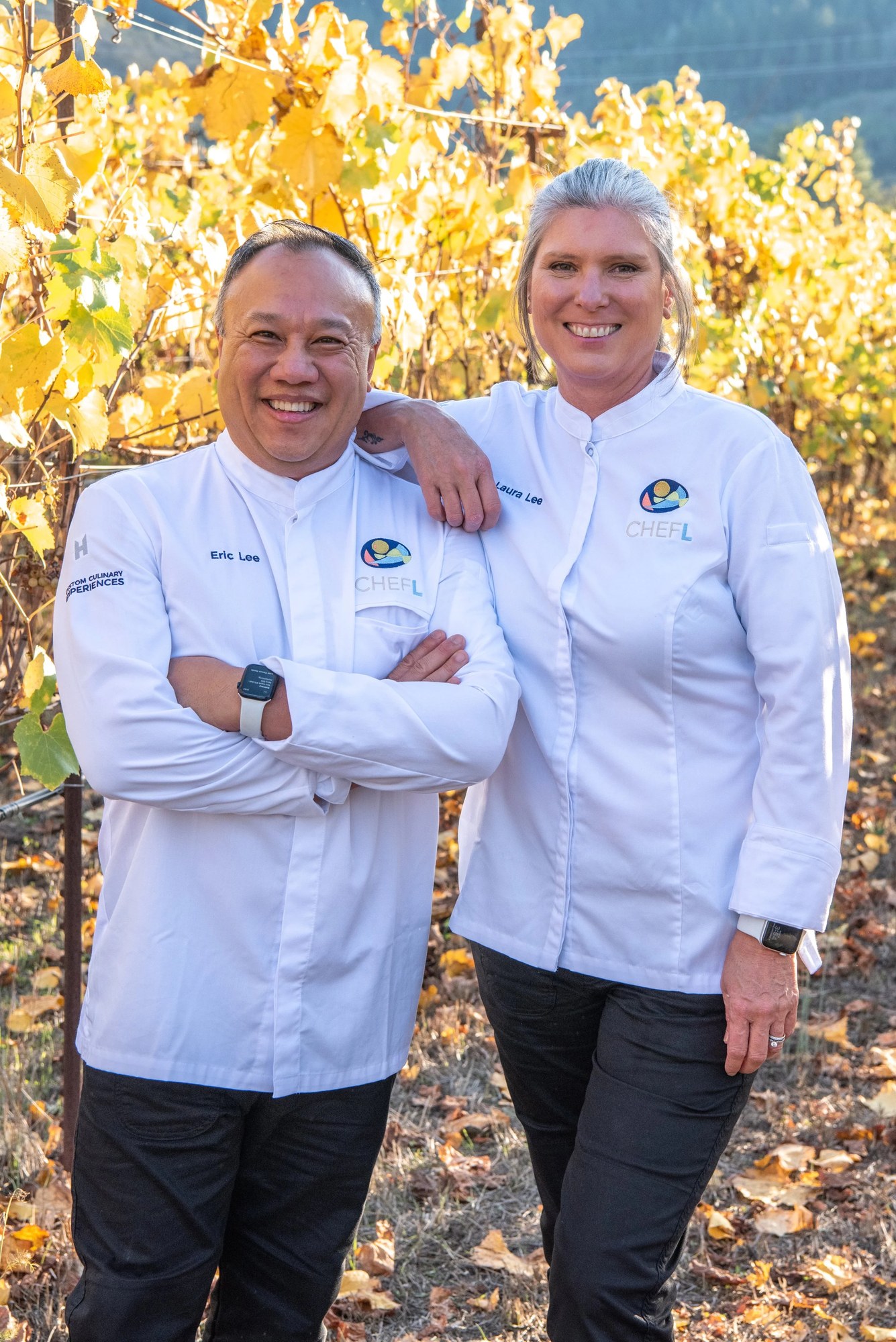 Chefs Eric and Laura Lee standing together in a vineyard.