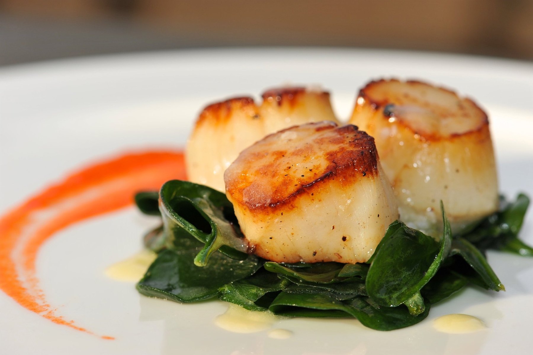 Seared scallops on wilted greens, a course from a Chef L Culinary pairing dinner.